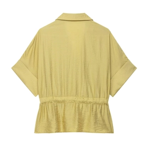 Vue détaillée d'une chemise en satin jaune moutarde avec taille à cordon et texture lisse