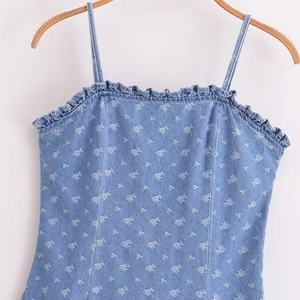 Blue denim camisole dress with white floral pattern and ruffled neckline on wooden hanger