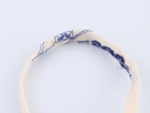 Detail of beige cotton linen fabric with navy blue embroidery and rustic frayed edges
