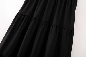Detailed view of layered pleats and black woven fabric stitching on the midi dress