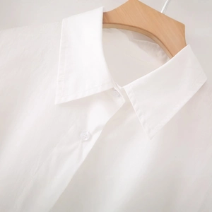Minimalist white cotton poplin shirt with pointed collar and irregular split hem style