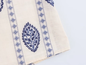 Detailed close-up of navy blue floral embroidery on off-white cotton linen midi dress