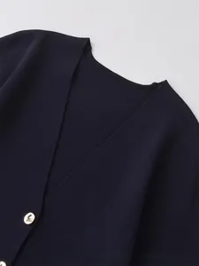 Detail of navy knit cardigan with V-neckline and polished gold metal button closure
