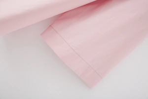 Close-up of the baby pink shirt cuff showing detailed stitching and fine fabric texture