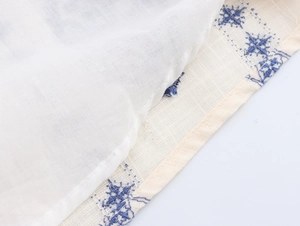 Detail of blue star embroidery on breathable beige cotton-linen midi dress fabric