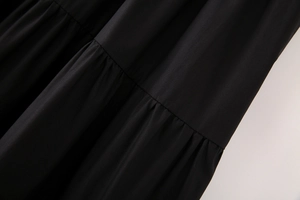 Detailed macro view showing the gathered tiered seams and black fabric texture of the dress