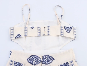 Detail of white midi dress showing blue geometric embroidery and back button closure