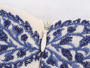 Close-up of invisible zipper and blue leaf embroidery on beige linen midi dress