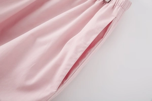 Detail of pink woven trousers showing elastic waistband, side pocket and fine texture