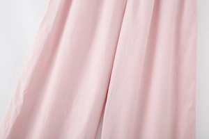 Detail view of the light pink fabric texture on wide leg trousers with a soft matte finish
