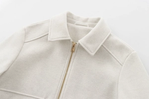 Detail of off-white woolen jacket featuring a modern gold metal zipper and minimalist collar