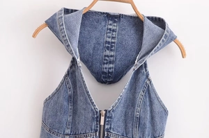 Dettaglio del top in denim blu lavato con cappuccio e cerniera metallica resistente
