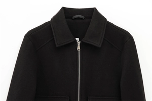 Detail of silver metal zipper and lapel collar on a textured black zip-up jacket