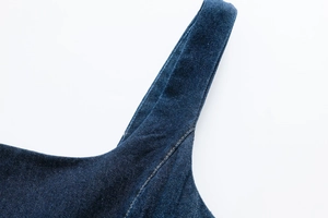 Detail of wide shoulder straps and contrast stitching on dark blue denim dress