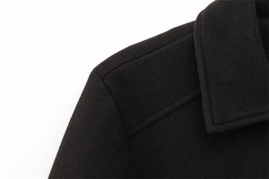 Macro detail of high-quality black wool coat showing premium fabric texture and shoulder seams