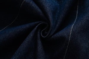 Detailed close-up of dark indigo denim fabric with orange contrast double stitching