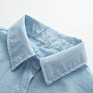 Close-up of light blue short-sleeve shirt collar with textured fabric and button detail