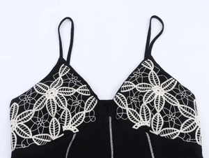 Detail of black camisole dress featuring intricate white floral embroidery and contrast stitching