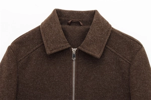 Detail of a brown wool jacket featuring a silver metal zipper and classic lapel collar