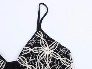 Detail of white floral lace embroidery on black camisole dress with spaghetti straps