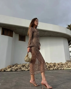 Detailed view of a sequined brown long-sleeve dress with shiny metallic handbag for evening