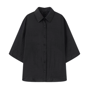Close-up of black short-sleeved shirt with crinkle texture and classic lapel collar