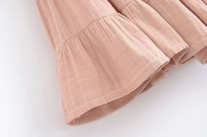 Gros plan détaillé du tissu plissé rose montrant la texture crêpe et les volants