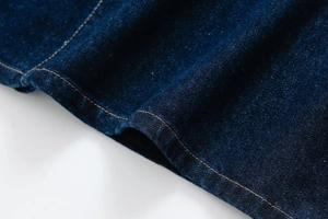Detail of dark blue denim hem with contrast orange stitching and high-quality twill texture