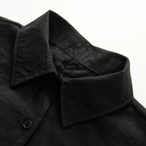 Detailed close-up of a classic black shirt collar with neat stitching and resin buttons