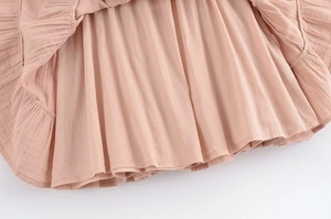 Détail de l'ourlet de la robe plissée rose montrant le coton doux et la doublure volantée