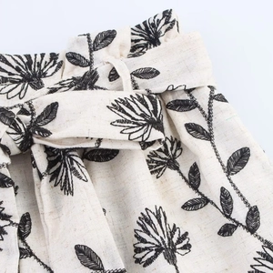 Short taille haute beige avec broderies florales noires et ceinture à nouer