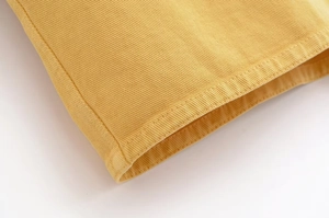Gros plan des coutures de l'ourlet d'une veste en jean jaune vif pour femme en coton