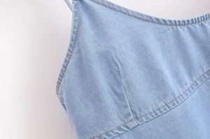 Detail of light blue denim top featuring yellow contrast stitching and curved seams