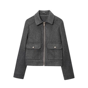 Detail of dark gray tweed short jacket with zipper closure and gold button pockets