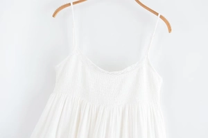 Détail de robe blanche à fines bretelles avec dentelle et texture buste smocké