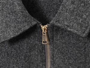 Detailed macro view of high-quality gold metal zipper on soft grey wool jacket fabric