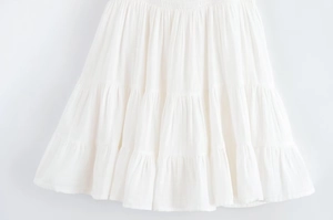 Détail d'une robe blanche à volants avec taille élastique froncée et jupe à plusieurs niveaux