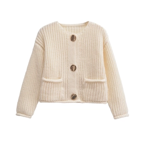 Detail of cream knit cardigan featuring golden metal buttons and textured front pockets