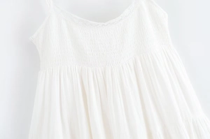 Détail de robe blanche en tissu froncé avec dentelle délicate et fines bretelles
