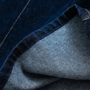 Close-up of dark blue denim dress fabric with contrast orange stitching details