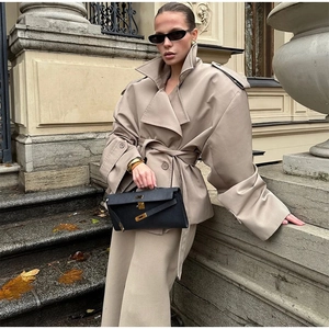 Detail of khaki trench coat set featuring wide lapels and epaulettes on a city street