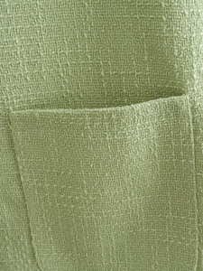Detail of mint green tweed fabric showing woven texture and stitched pocket design