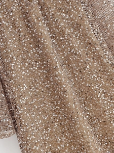 Detailed macro shot of shimmering rose gold sequins on a stylish cocktail dress fabric