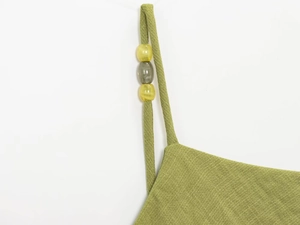 Detail of green summer dress shoulder strap with decorative beads and linen texture