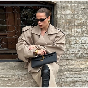 Detail of oversized khaki trench coat with wide shoulders and large lapels on a model