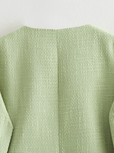 Close-up of light green tweed fabric texture and back neckline of a casual autumn jacket