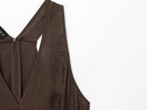Détail d'une robe en lin marron montrant le col en V avec fermeture éclair et étiquette