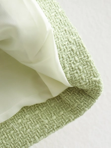 Detailed close-up of light green tweed fabric texture and white inner lining finish