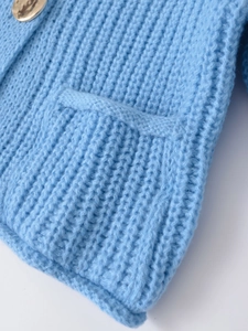 Detail of light blue knit sweater featuring ribbed texture and golden button on the pocket
