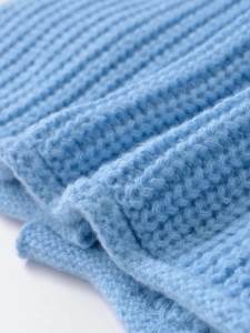 Detailed macro view of soft sky blue ribbed knit fabric texture on a long sleeve sweater